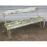 A late 19th/early 20th century green painted teak & wrought-iron garden bench on scroll-shaped end