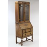 A 1930’s oak bureau-bookcase the upper part with two adjustable shelves enclosed by pair of glazed