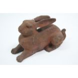 A large cast-iron garden ornament in the form of a recumbent hare, 14” wide.