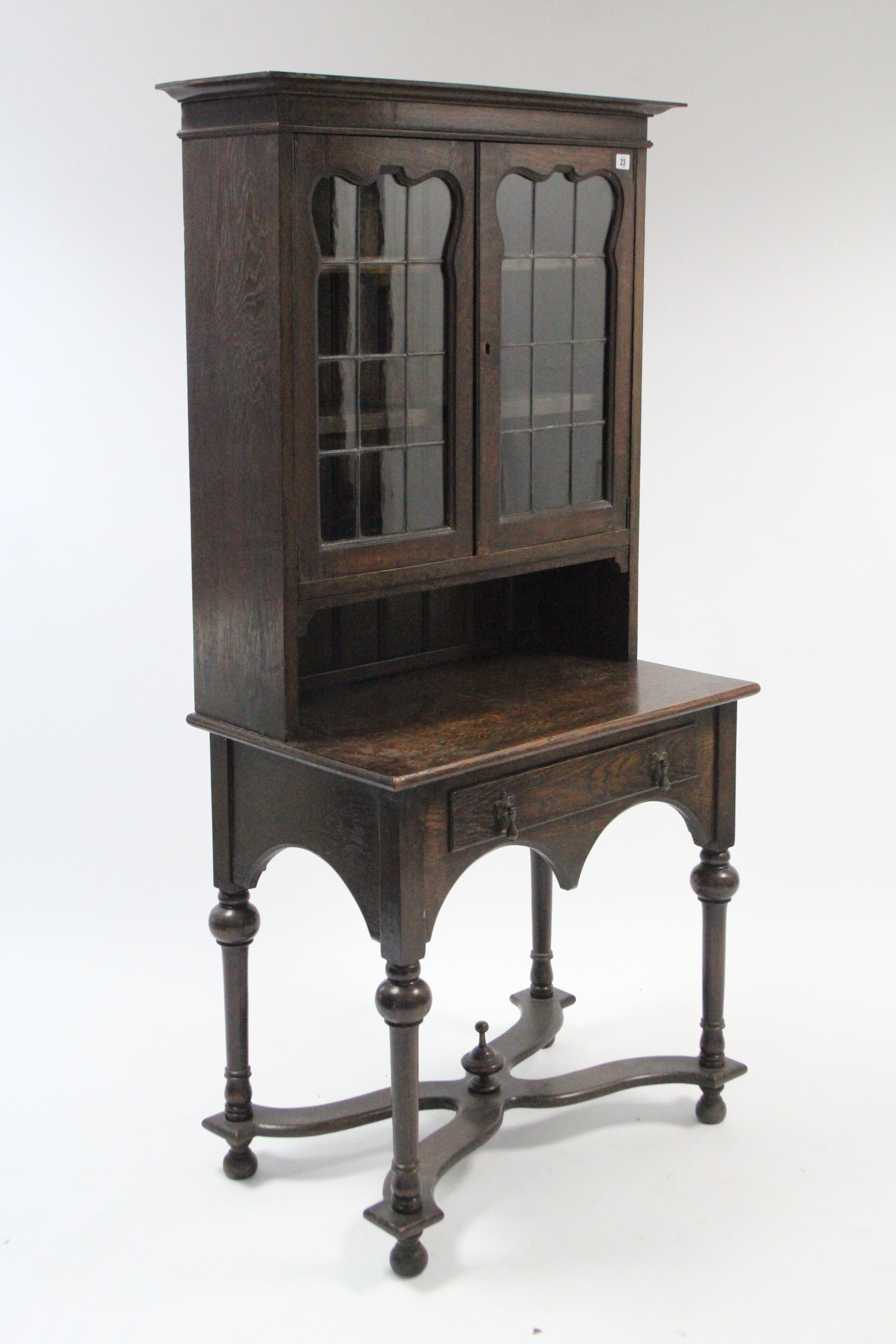 A 1930’s oak small bookcase the upper part with two adjustable shelves enclosed by pair of leaded