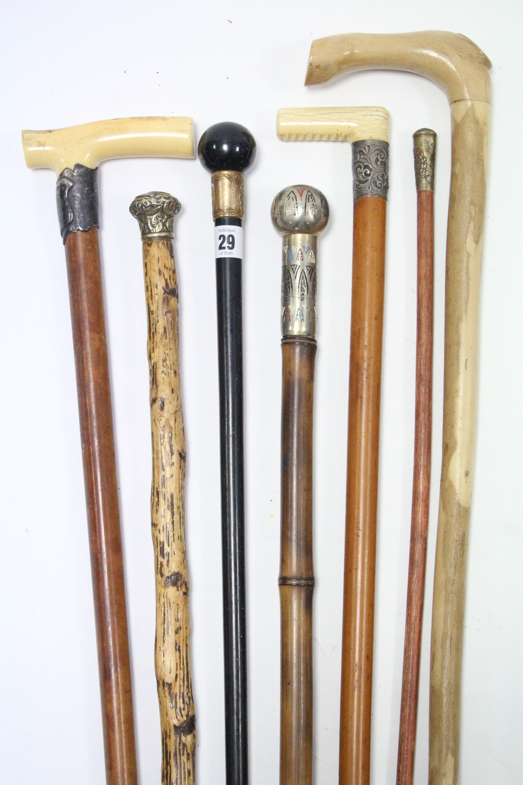 An Edwardian ebonised gent’s walking cane with 18ct. gold plated mount; together with five other