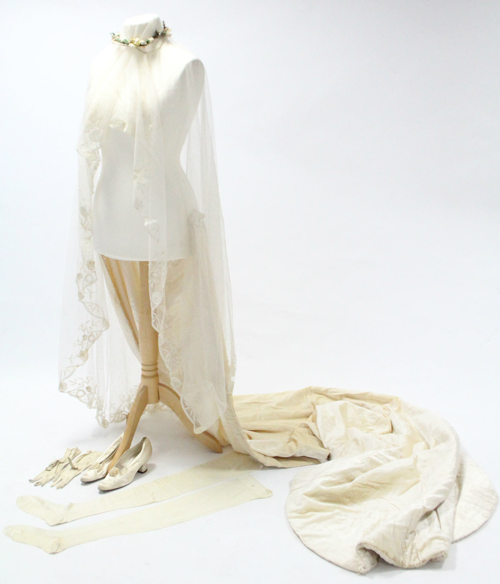 An early 20th century cream wedding outfit comprising a train, veil, headdress, pair of gloves, pair