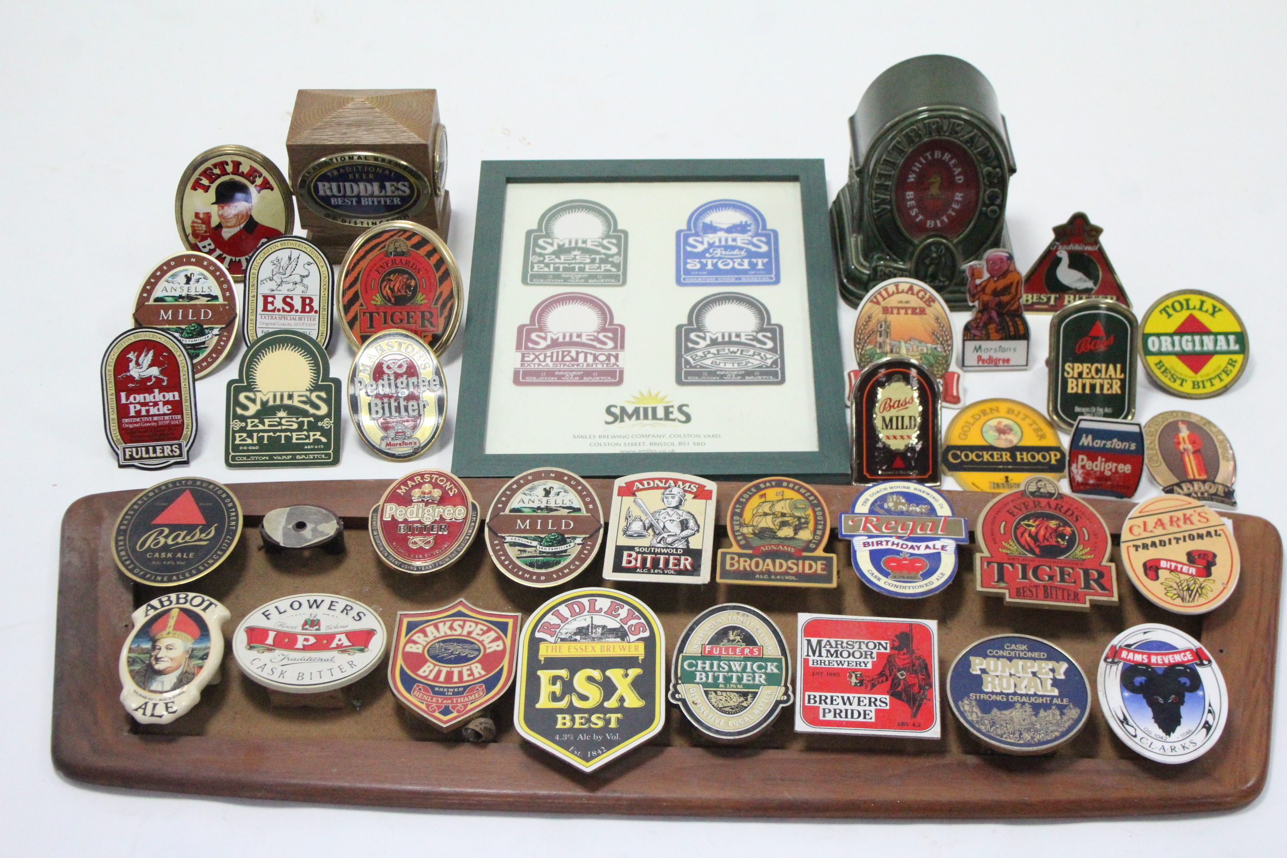 A collection of sixteen beer pump name plates mounted on wooden board; together with various other