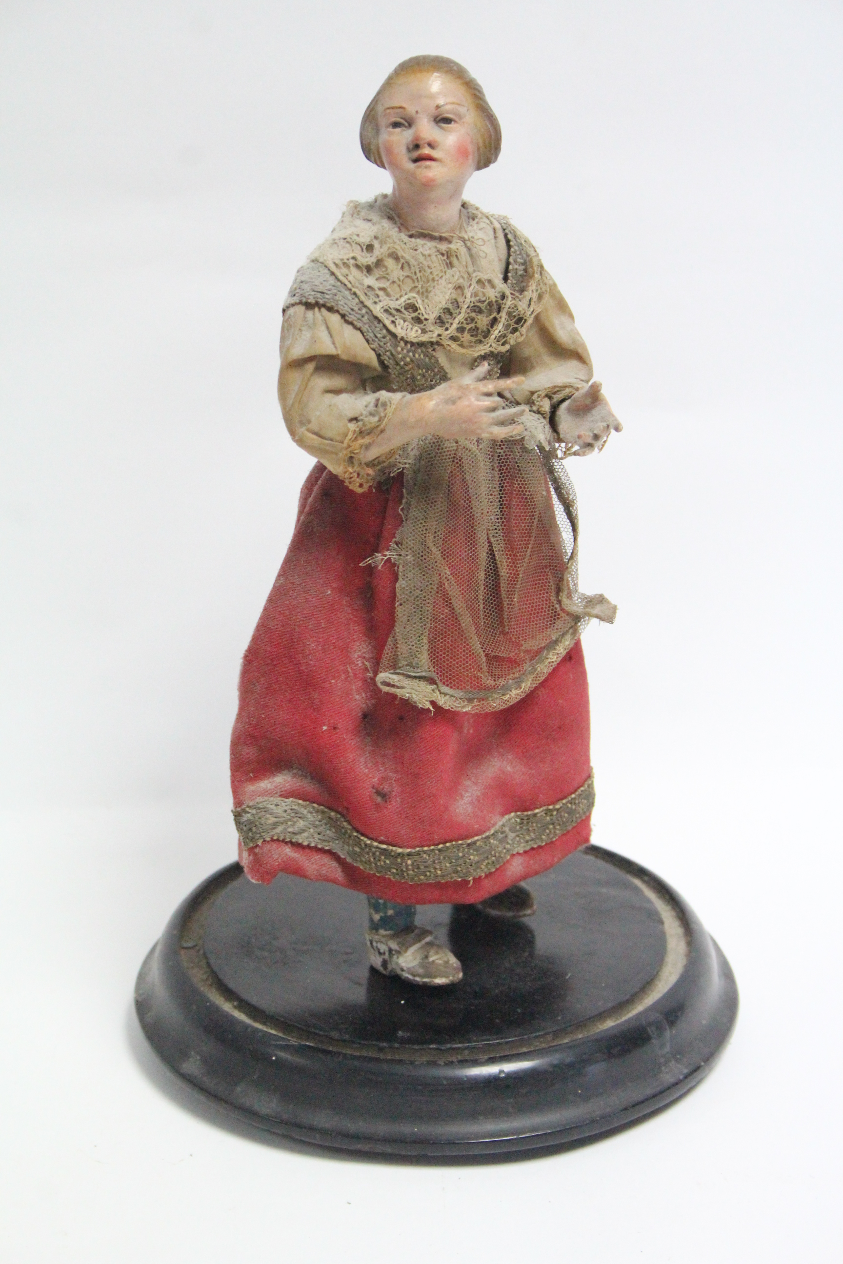 A painted composition peddler doll mounted on ebonised wooden plinth, 11½” high.