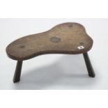 An oak milking stool by JACK GRIMBLE, the shaped seat with carved Tudor rose, on three chamfered