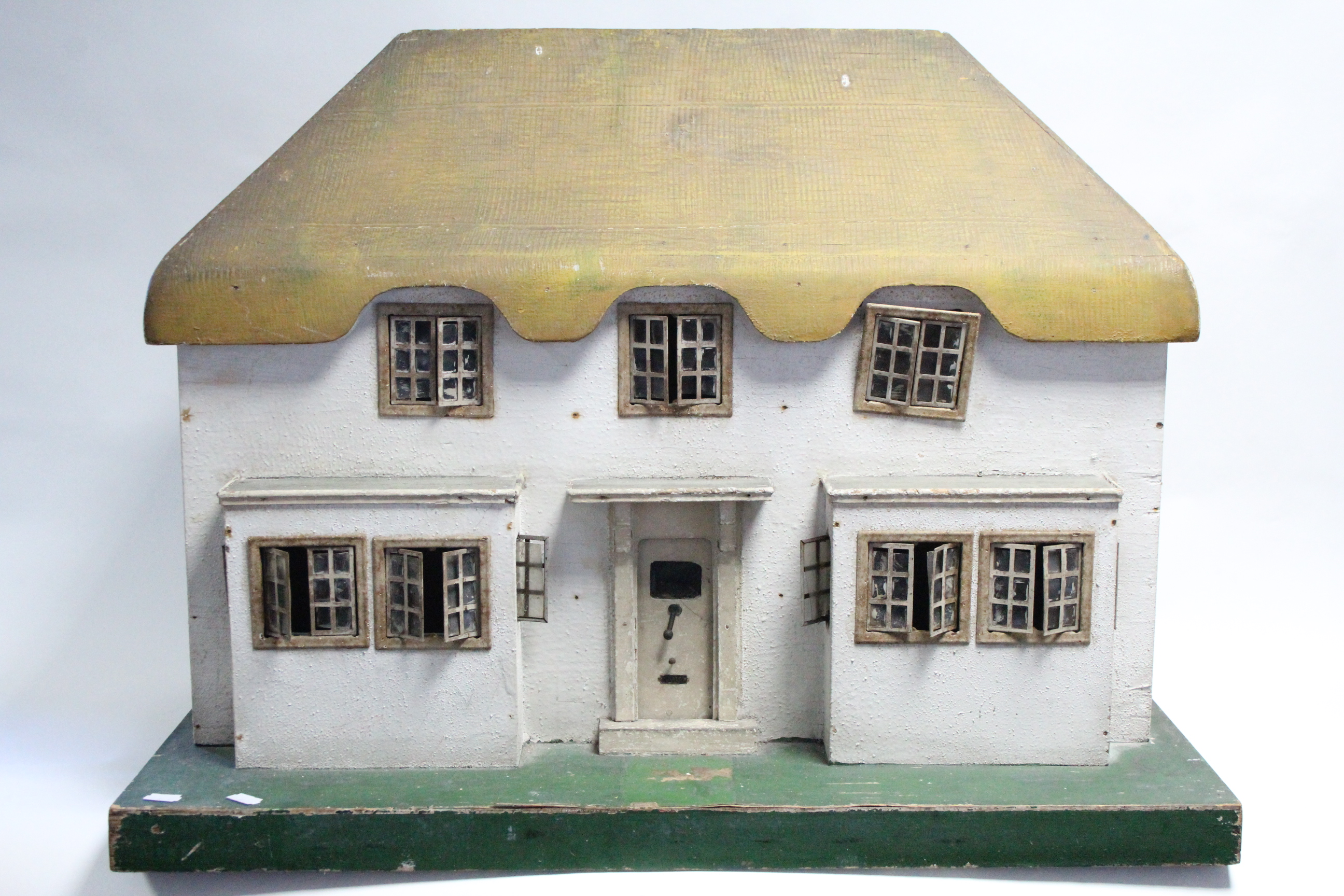 An early-mid 20th century Tri-ang painted wooden cottage-style two-storey doll’s house, with opening