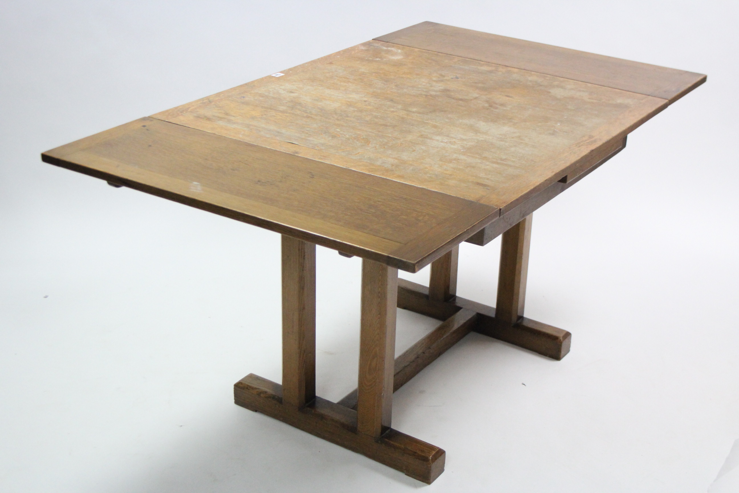 A mid-20th century oak draw-leaf dining table on pair of square tapered end supports to either end