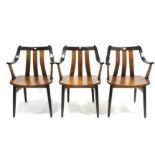 Three Anthropologie teak rail-back elbow dining chairs with hard seats &on round tapered legs.