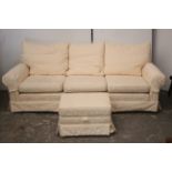 A modern three-seater settee with loose cushions to the seat & back upholstered salmon pink &