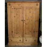 A large pine wardrobe with moulded cornice, enclosed by pair of panel doors above two drawers & on