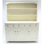 A cream painted pine dresser, the upper part fitted two open shelves & with panelled back, the