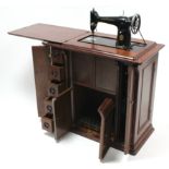 A singer treadle sewing machine in walnut case, 32" wide.