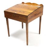 A pitch pine sloping-front clerk’s desk enclosed by hinged lift-lid, & on square tapered legs,