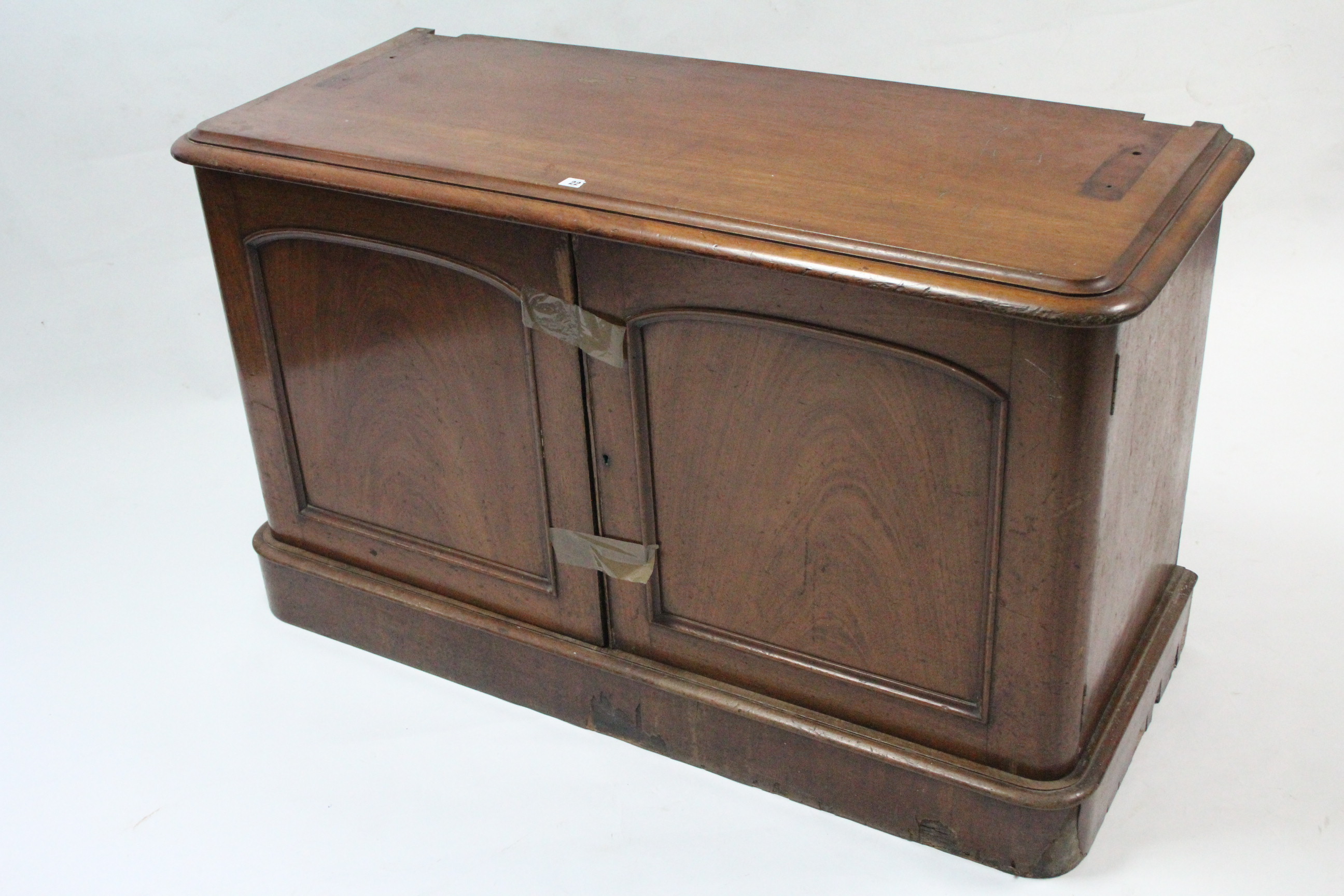 A Victorian mahogany low cupboard, fitted two shelves enclosed by pair of panel doors, & on plinth