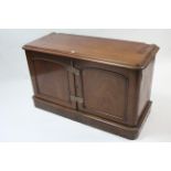 A Victorian mahogany low cupboard, fitted two shelves enclosed by pair of panel doors, & on plinth