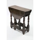 An early 18th century oak small oval gate-leg table on baluster-turned supports with plain