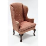 An 18th century-style wing-back armchair upholstered floral silk damask, with curved arms, & on