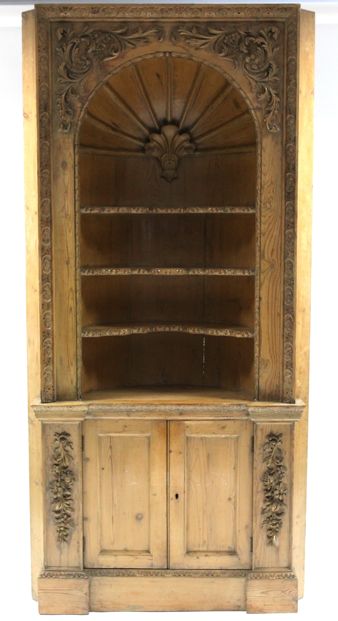 An 18th century pine alcove cabinet, the upper part with barrel-back centred by a shell above