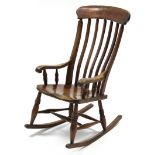 A Windsor style lath back rocking elbow chair with turned supports.