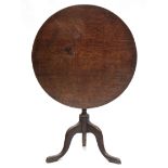 A late 18th century oak tripod table, the circular tilt-top on vase-turned centre column &