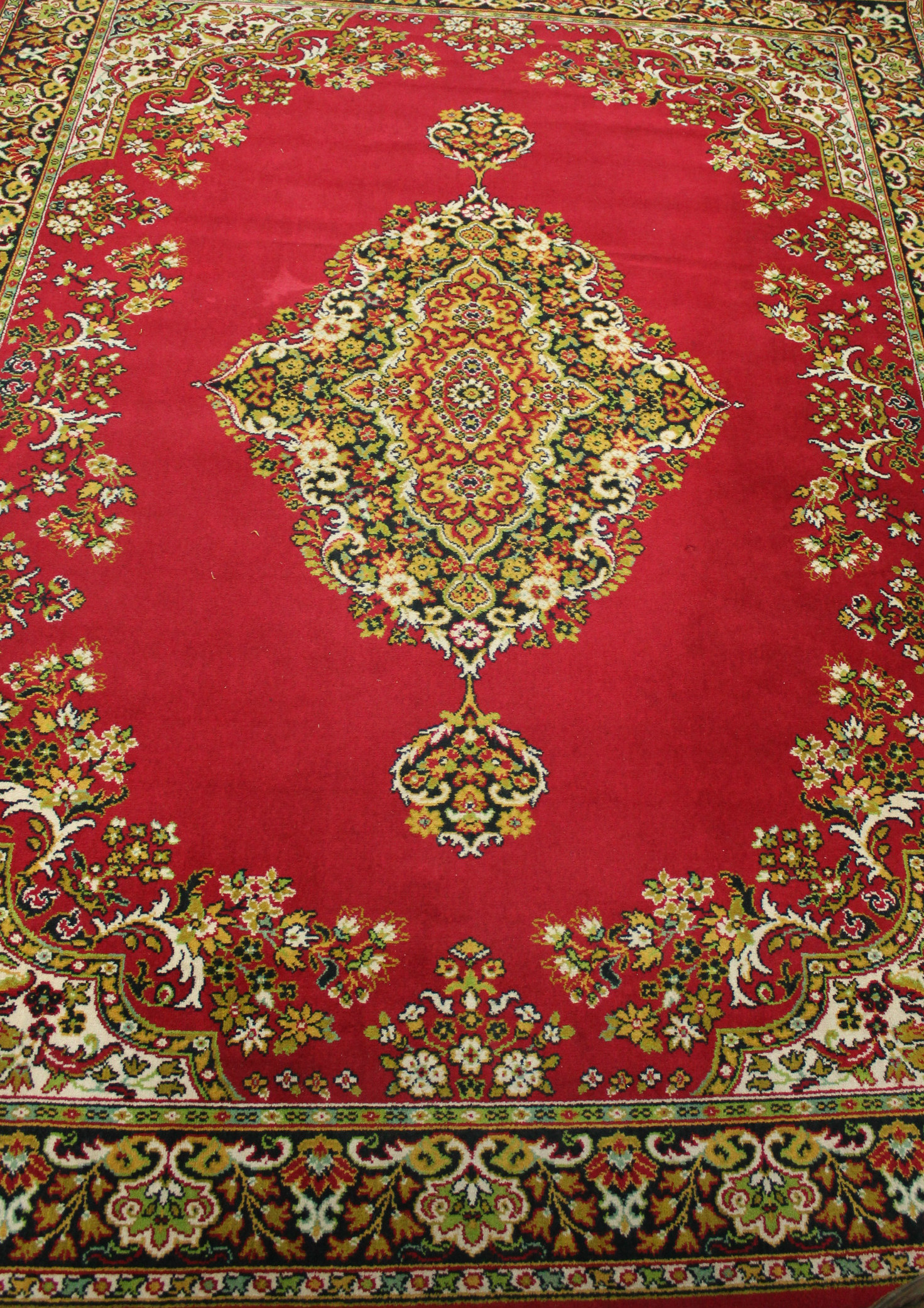 An Axminster-type Persian pattern carpet of crimson ground central medallion surrounded by floral