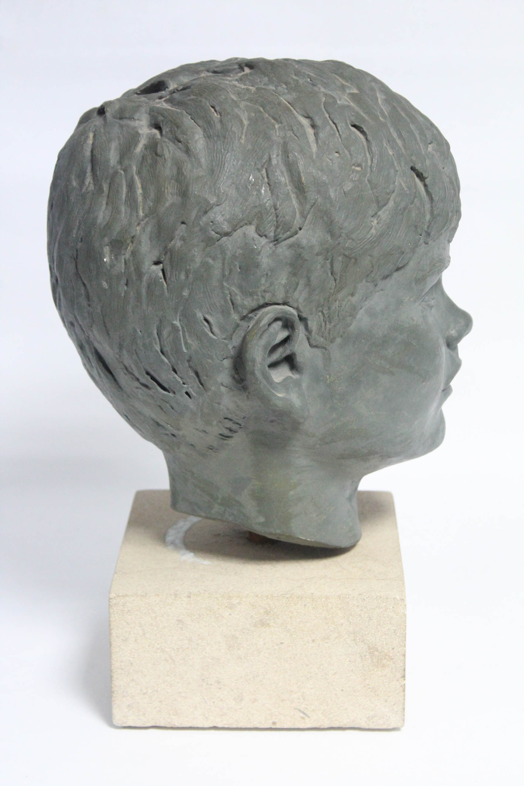 A green painted plaster head of a young boy, on stone block base; 13½” high over-all. - Image 3 of 4