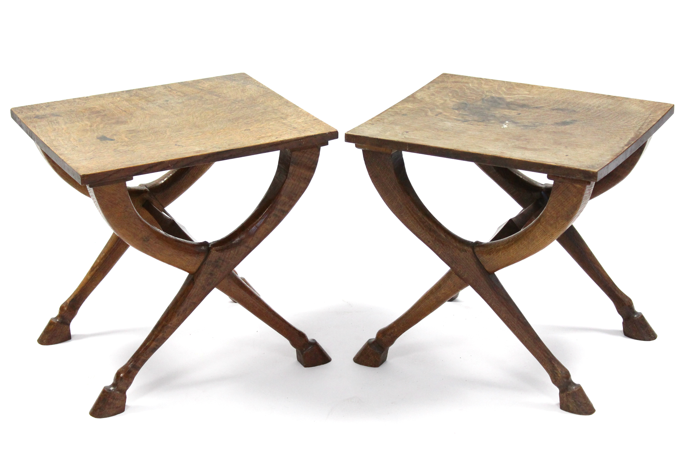 A pair of Victorian oak stools with rectangular hard tops, on curved "X" supports with hoof feet;