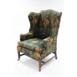 A late 18th century upholstered wing-back armchair on moulded square legs with castors.