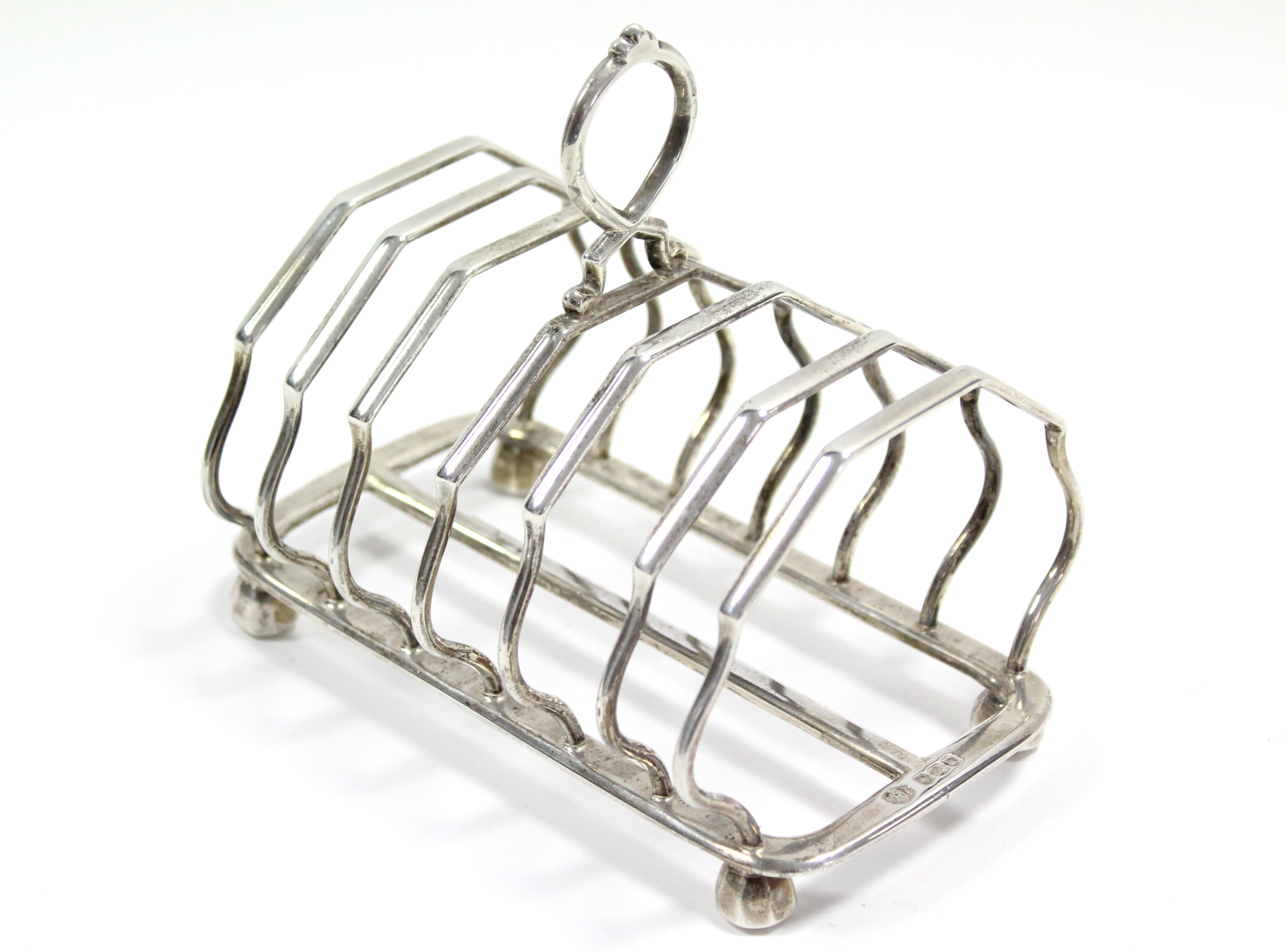 A George V six-division toast rack with centre ring handle, on four octagonal bun feet, 5¼” long;