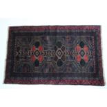 A Baluchi rug of dark blue ground with all-over repeating geometric design in blue, red, green &