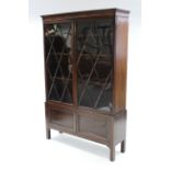 An early 19th century bookcase, on later stand, the upper section enclosed pair of lattice glazed