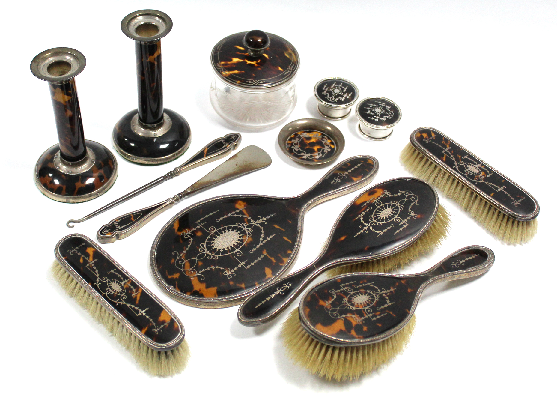 An Edwardian silver-inlaid tortoiseshell hand mirror, pair of matching clothes brushes, & hair