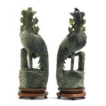 A PAIR OF CHINESE CARVED JADE MODELS OF PHOENIX, of mottled green colour, each with one leg