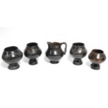 A group of four dark brown glazed earthenware vessels, each on pierced foot, 6” high; & a similar