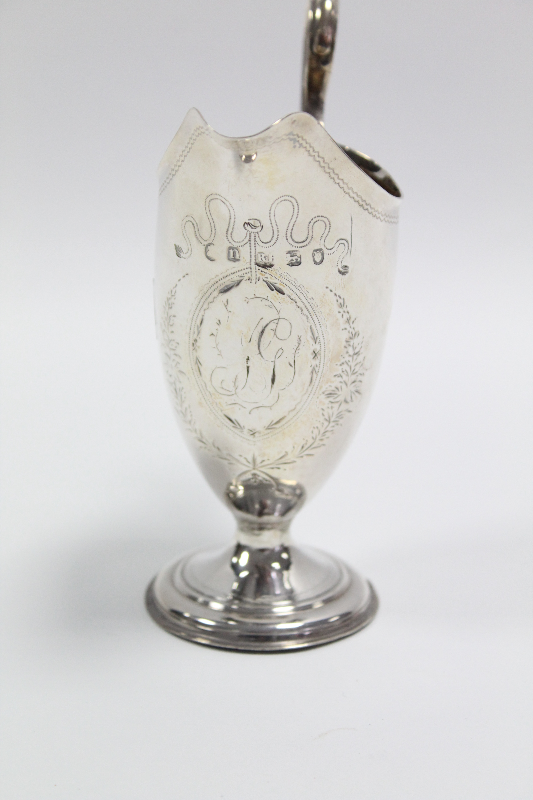A George III helmet-shaped cream jug with engraved monogram to an oval cartouche, loop handle, & - Bild 2 aus 2