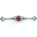 AN ART DECO BROOCH of narrow form, set central cabochon amethyst bordered by rows of small