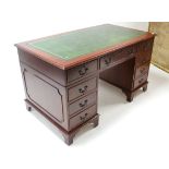 A reproduction mahogany pedestal desk inset gilt-tooled green leather cloth, fitted with an