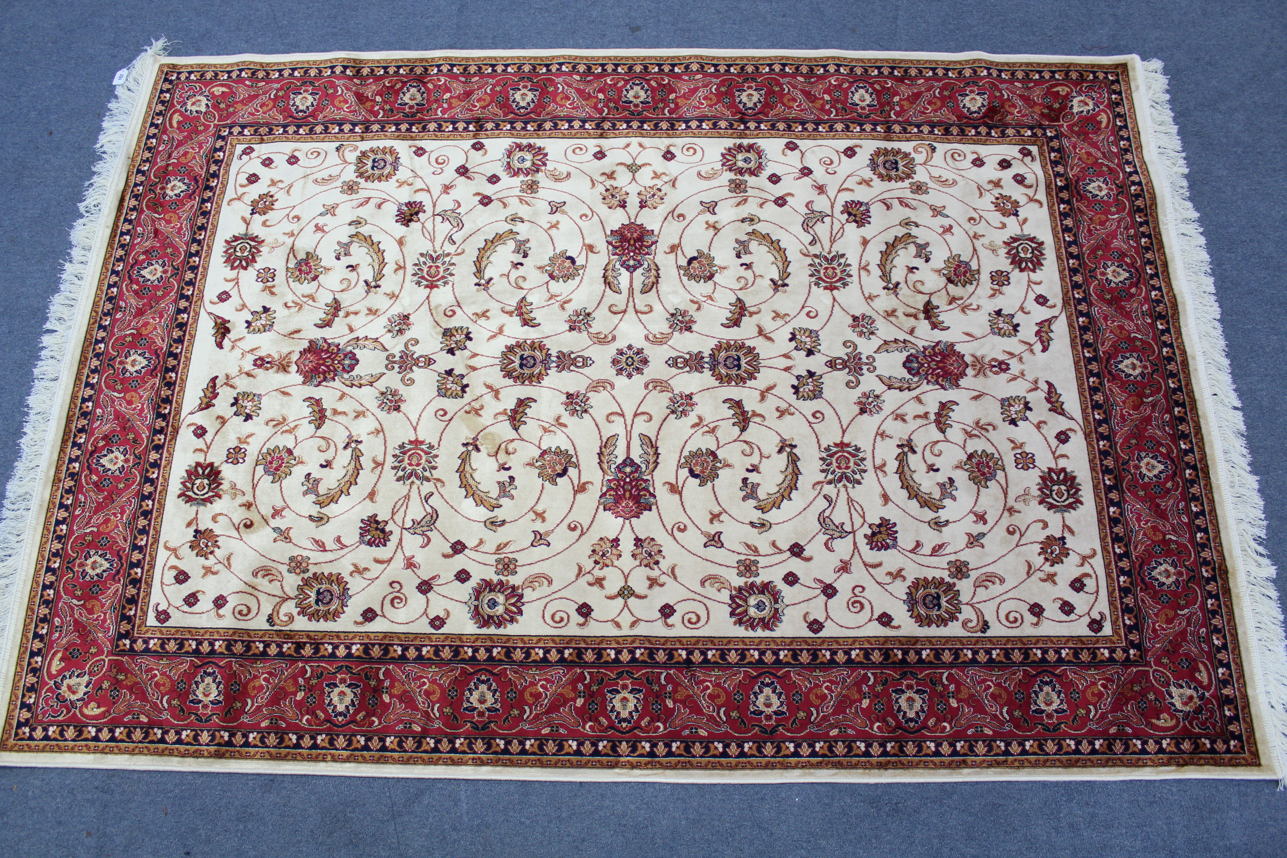 A Kashan carpet of cream & crimson ground, with multi-coloured geometric & floral design to centre