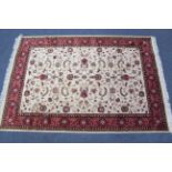 A Kashan carpet of cream & crimson ground, with multi-coloured geometric & floral design to centre