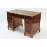 A reproduction yew wood pedestal desk inset gilt-tooled green leather cloth, fitted with an