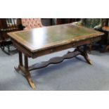 A reproduction carved mahogany writing table inset gilt-tooled green leather cloth to the