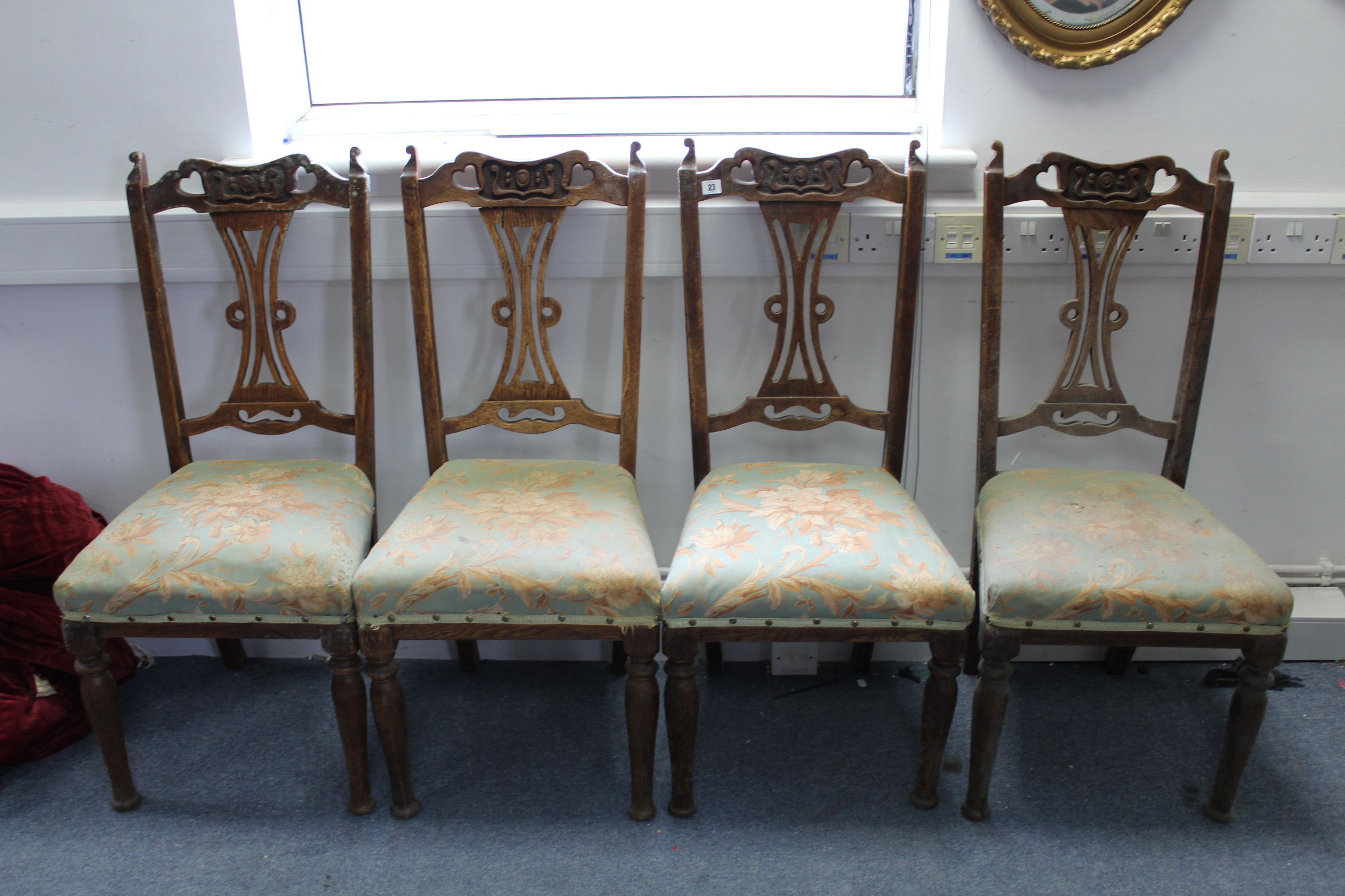 A set of four Edwardian carved oak splat-back dining chairs with padded seats, & on turned tapered