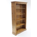 A pine tall standing open bookcase with four open shelves, & on shaped plinth base, 38” wide x