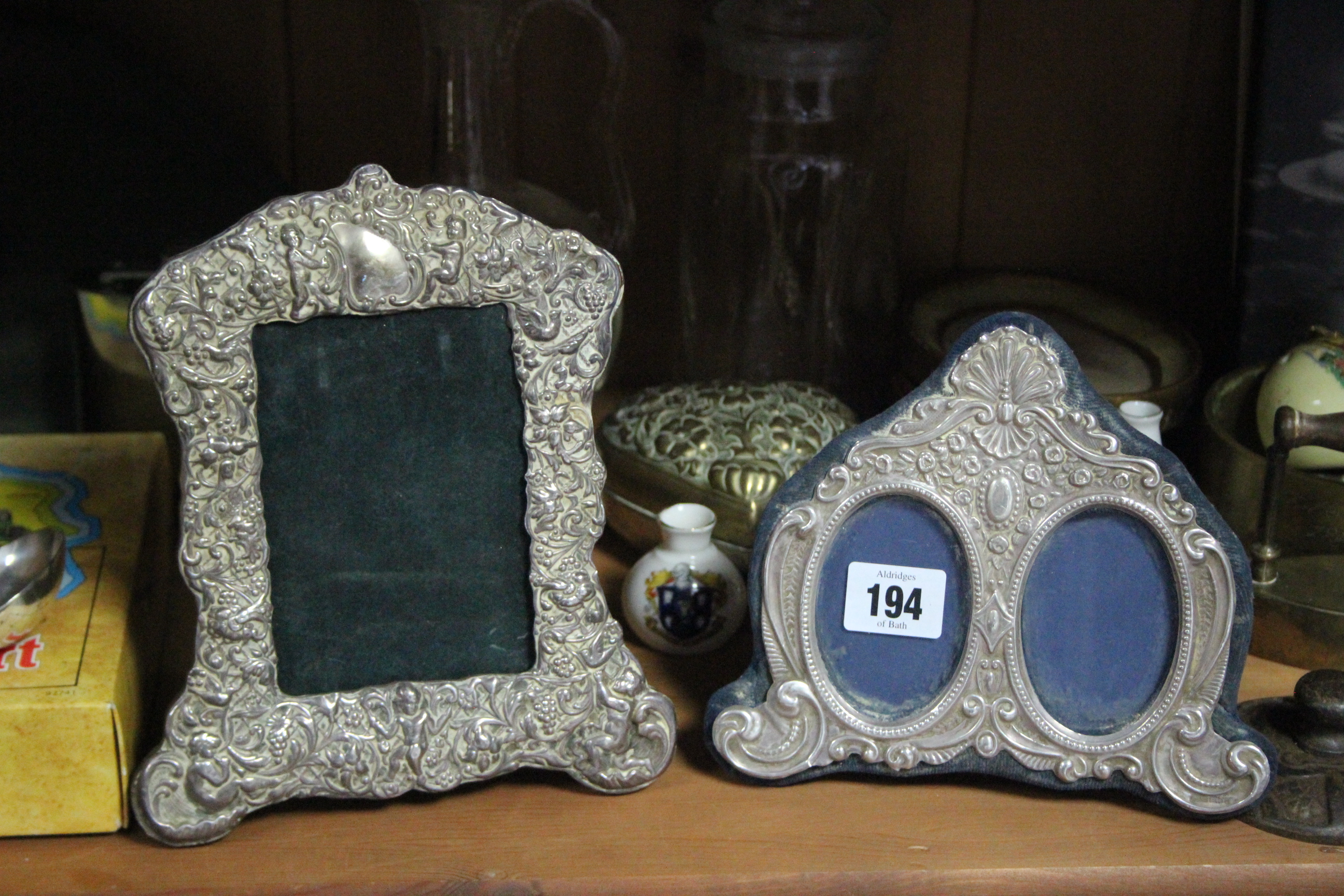 A silver embossed double photograph frame (hallmarks rubbed); a white-metal rectangular photograph