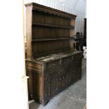 A reproduction carved oak dresser the upper part with two open shelves & with panelled back, the