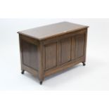 An oak coffer with hinged lift-lid, & with panelled front & sides, 37” long.