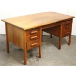 A teak kneehole office desk, fitted with an arrangement of two brushing slides & six drawers, & on
