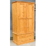 A large pine wardrobe with moulded cornice, enclosed by pair of panel doors above two short & one
