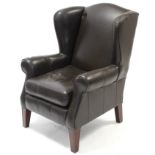 A Multiyork brown leather wing-back armchair, on short, square tapered legs.