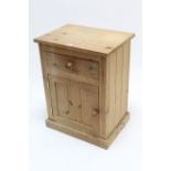 A pine bedside cabinet fitted frieze drawer above cupboard enclosed by pair panel doors, 19¼”